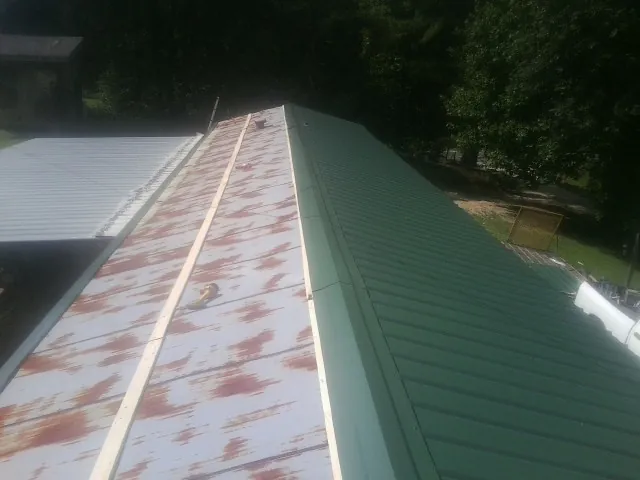 Old rusted panels beside newly installed green metal roofing — Wind Damage Roof Repair by Roofing Brothers in Worcester